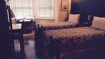 A hotel room with two beds, a dining table, and a chair.