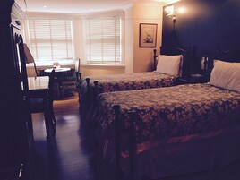 Una habitación de hotel con dos camas, una mesa de comedor y una silla.