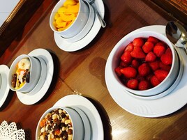Un plateau en bois contenant quatre bols remplis de différents fruits et de noix.