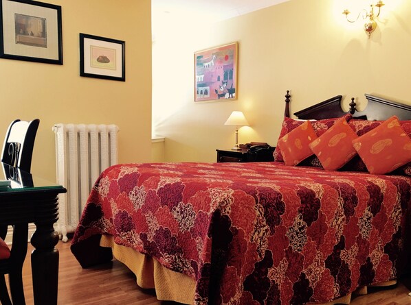 Un dormitorio ordenado con cama, una silla, un escritorio y una lámpara.