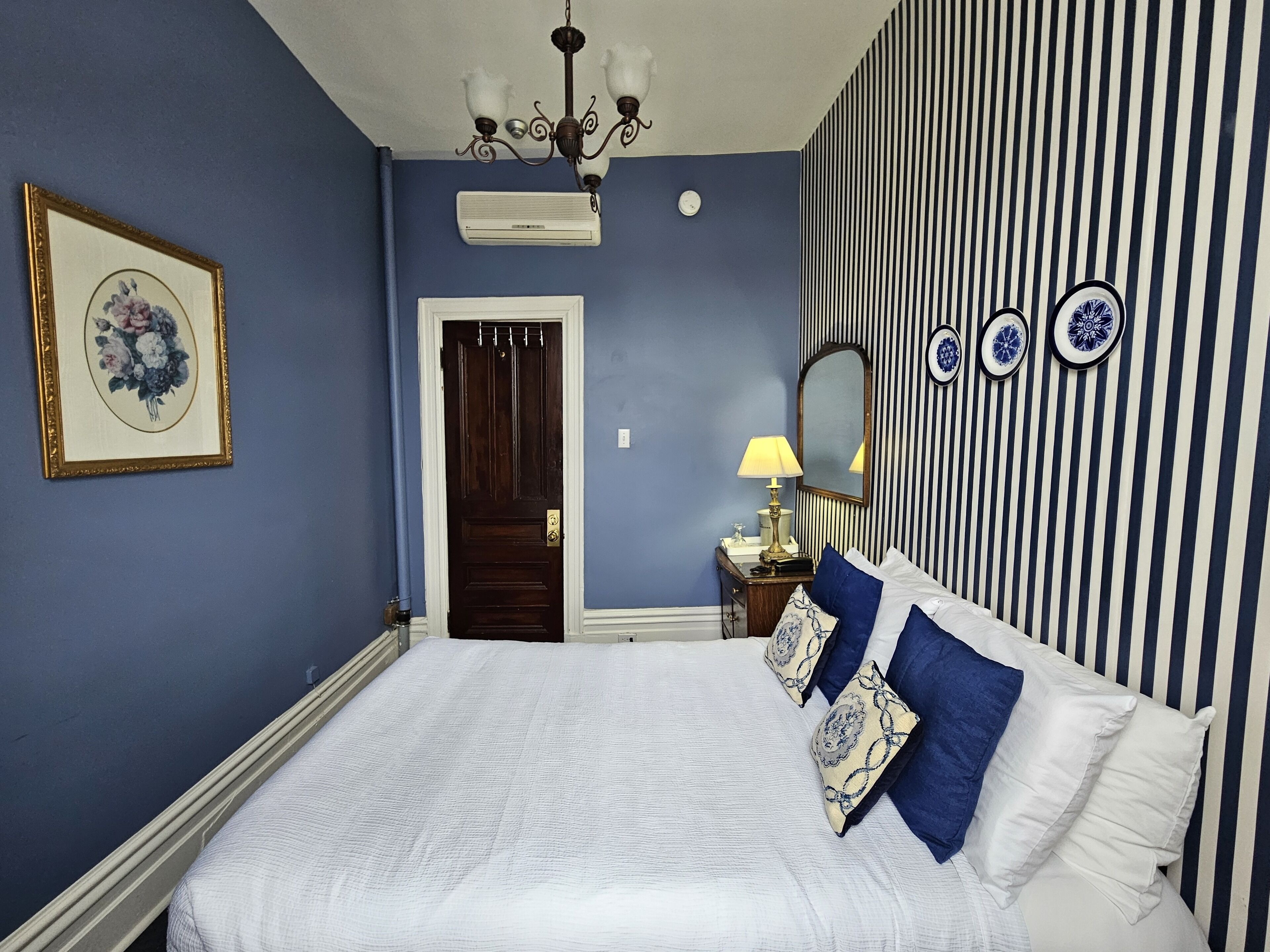 Quarto com cama, penteadeira, espelho, luminária e porta.
