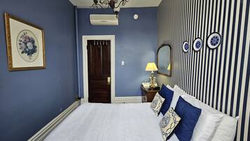 Une chambre à coucher avec un lit, une commode, un miroir, une lampe et une porte.