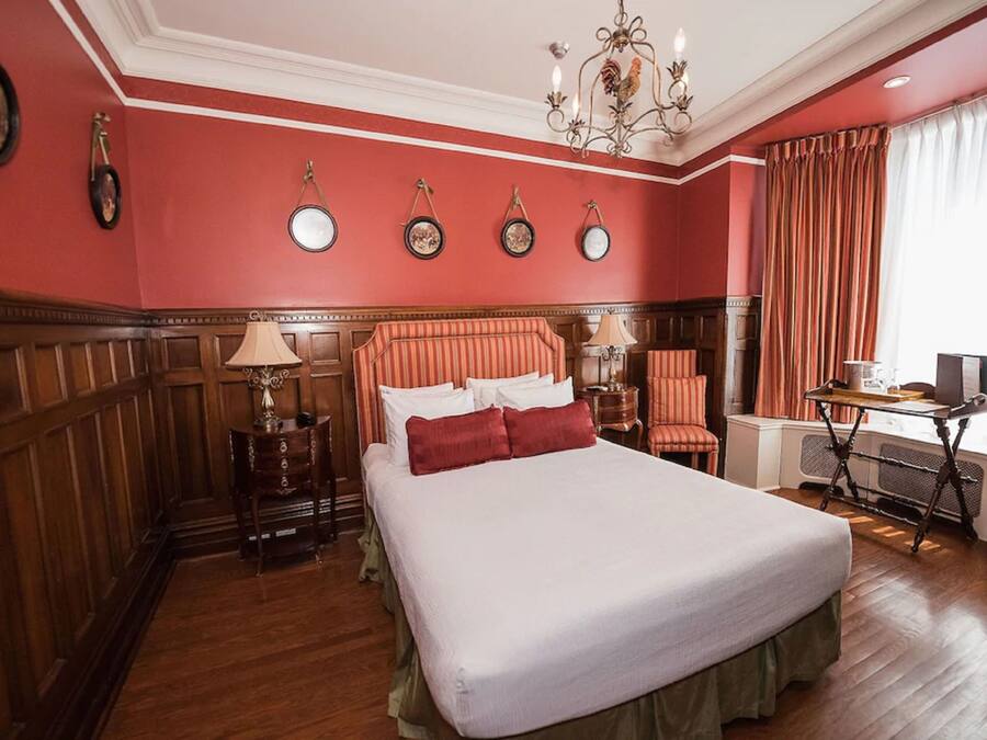 Una habitación de hotel con una cama grande, paneles de madera, un escritorio y una silla.