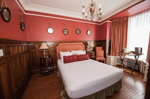 Una habitación de hotel con una cama grande, paneles de madera, un escritorio y una silla.
