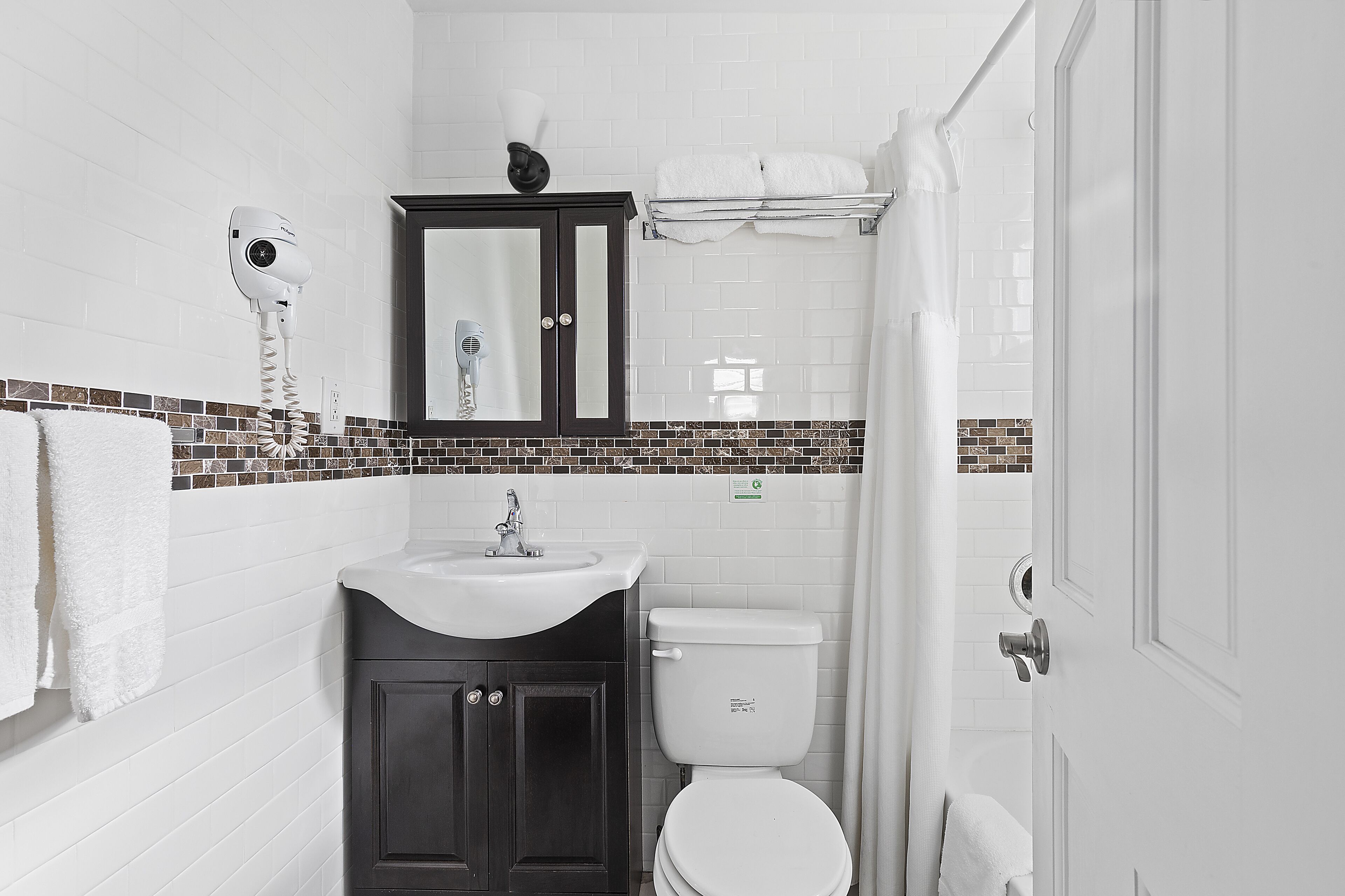 A bathroom with a white sink, dark cabinets, a white toilet, and a towel rack.