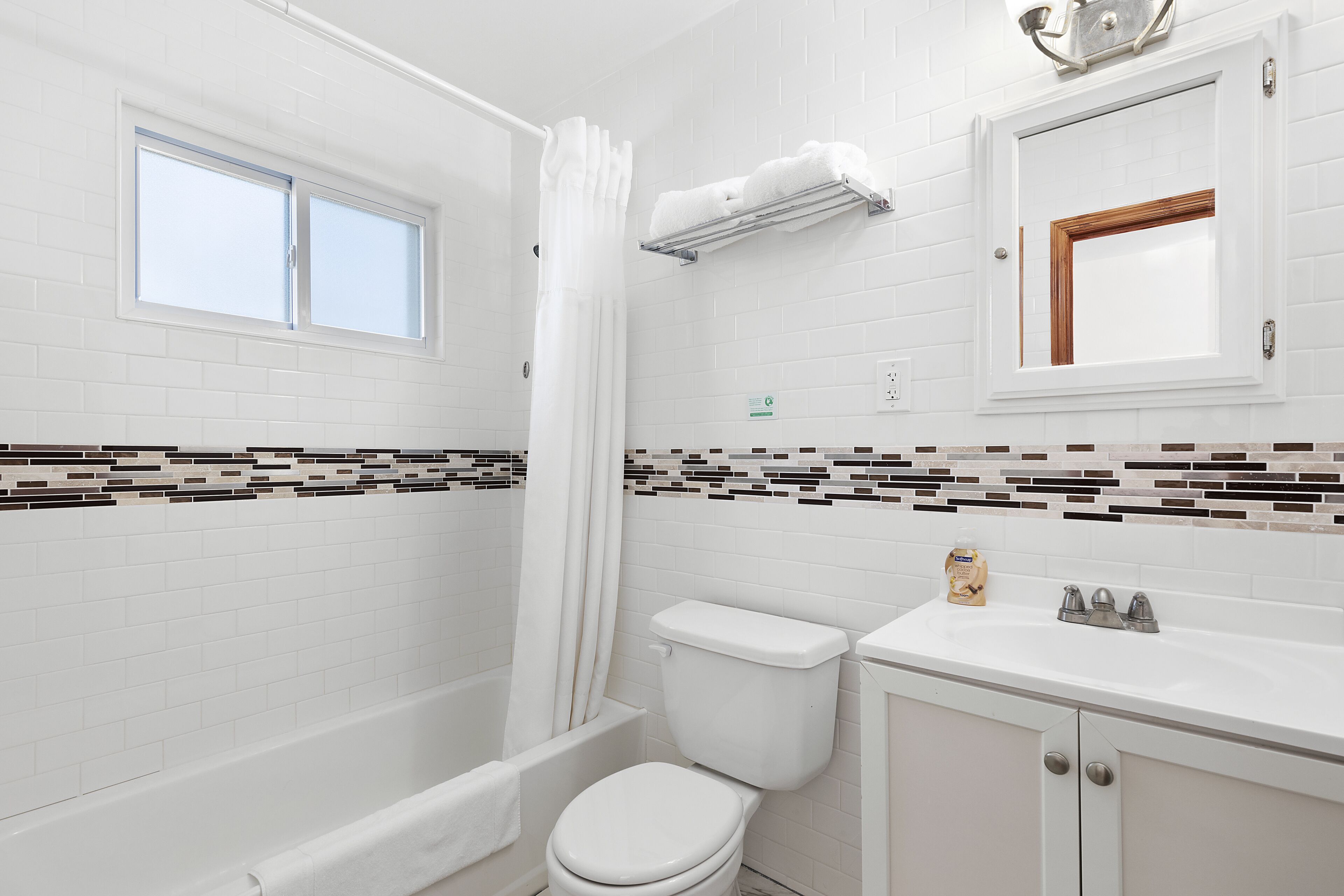 A bathroom with a bathtub, toilet, sink, and a window.