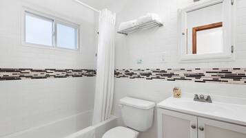 A bathroom with a bathtub, toilet, sink, and a window.
