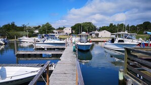 A marina with docked boats, a wooden pier, and a building in the background. - Baywatch Hotel & Marina (Hampton Bays)