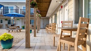 A covered outdoor seating area with wooden chairs and tables, potted plants, and hanging flower baskets. - Aqualina Inn Montauk (Montauk)