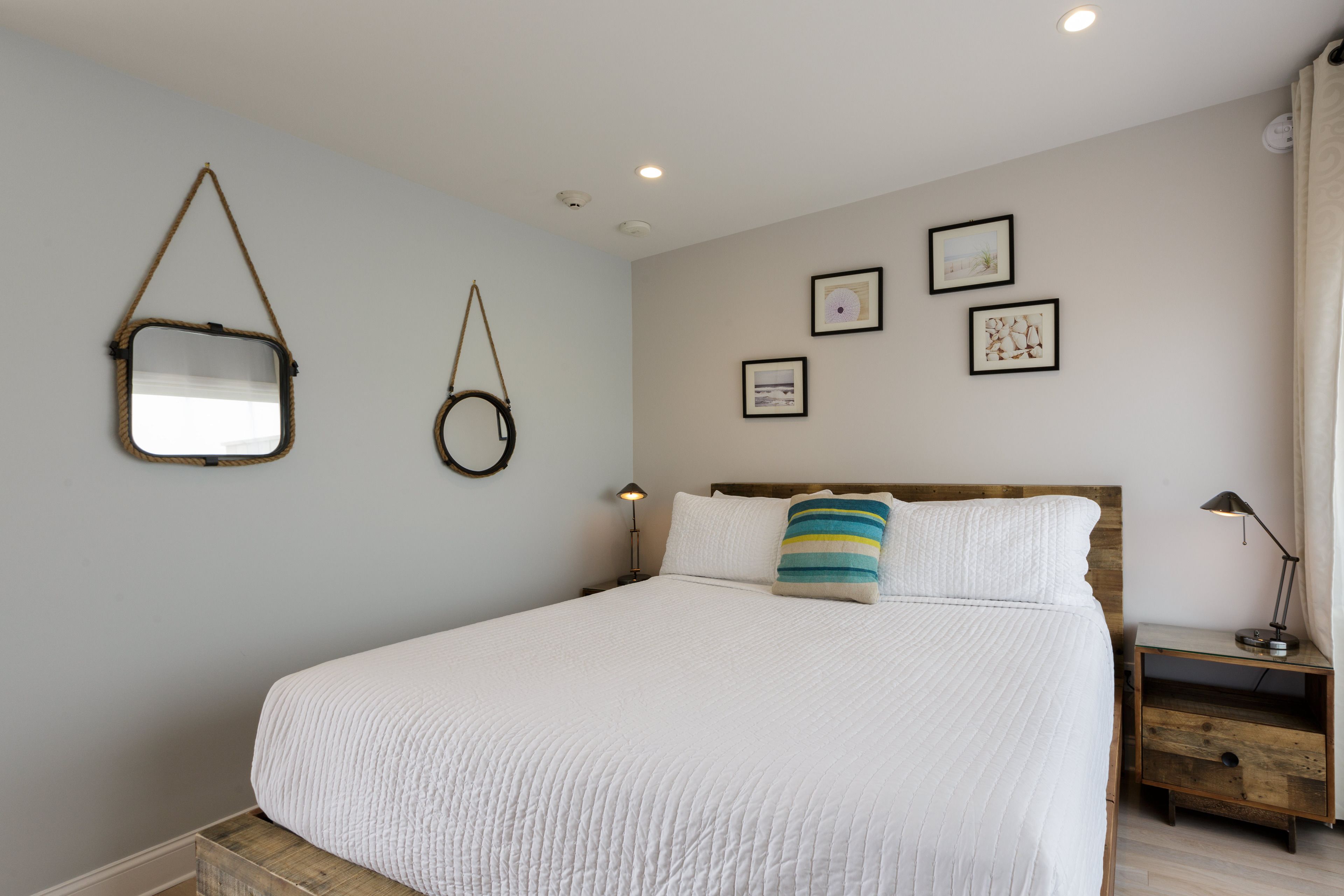 A bedroom with a bed, a nightstand, a lamp, and wall-mounted decor.