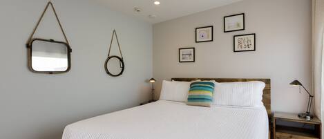 A bedroom with a bed, a nightstand, a lamp, and wall-mounted decor.
