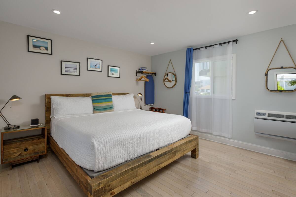 A bedroom with a wooden bed, bedside tables, a hanging light, and a window with curtains.
