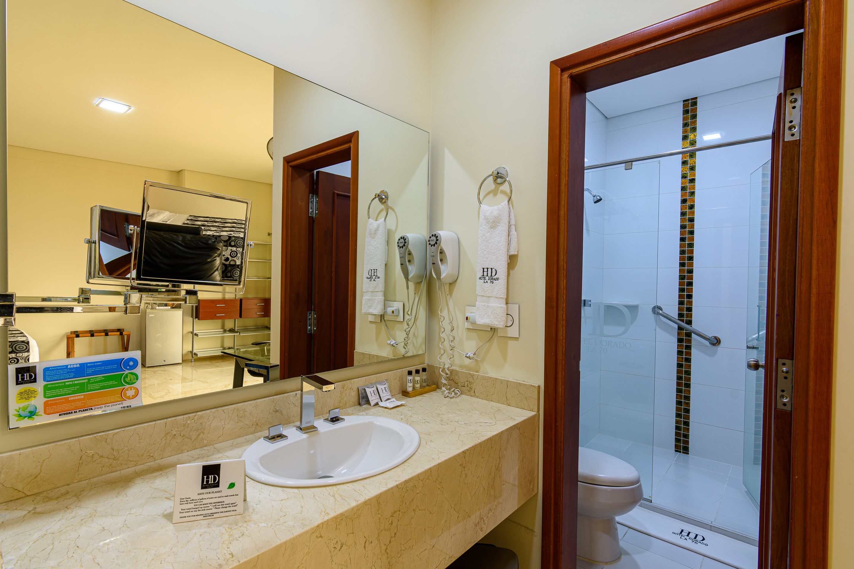 Ein Hotelbad mit Waschbecken, Spiegel und Dusche.