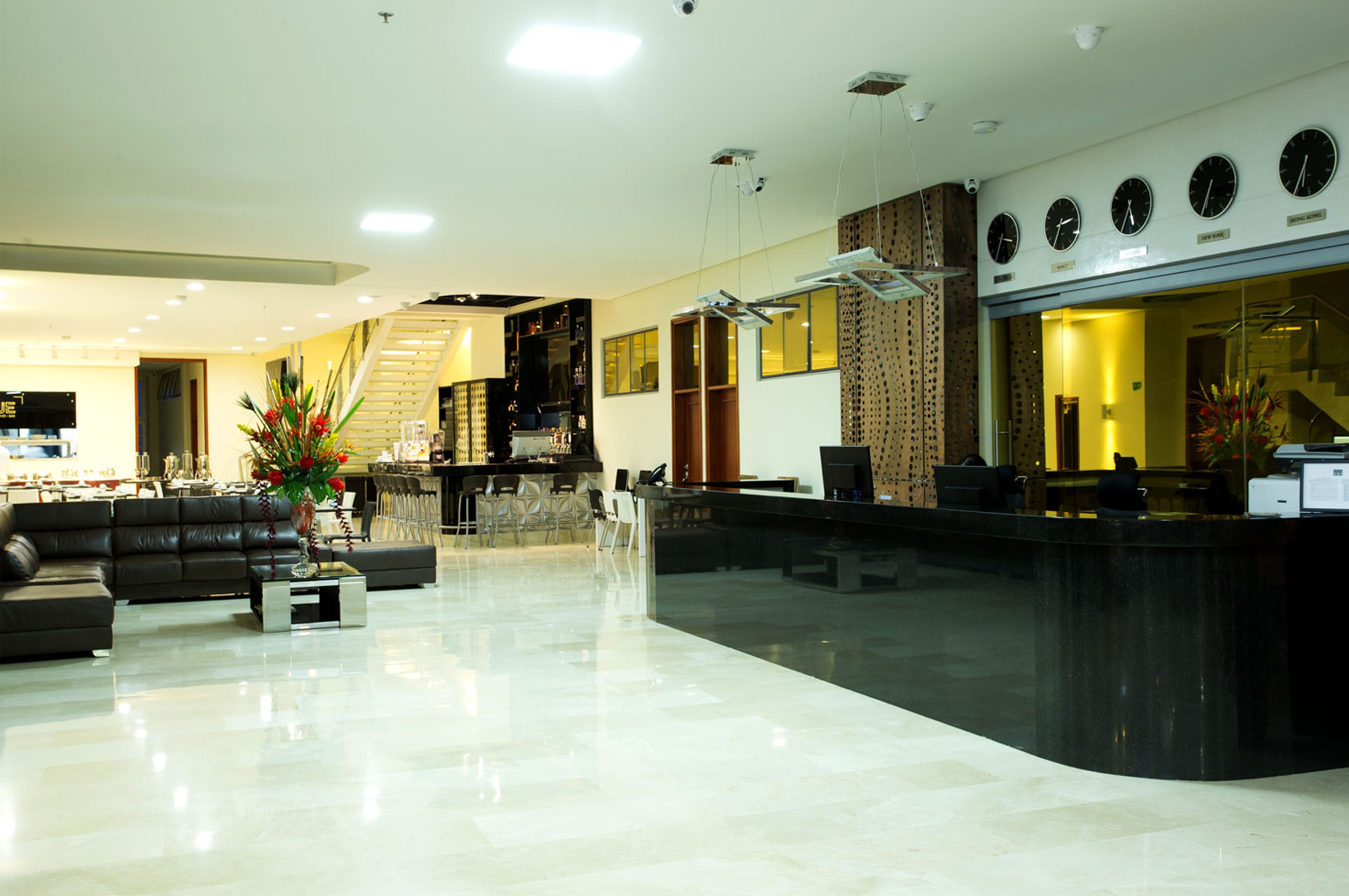 Un moderno vestíbulo de hotel con mostrador de recepción, zona de estar y una escalera.