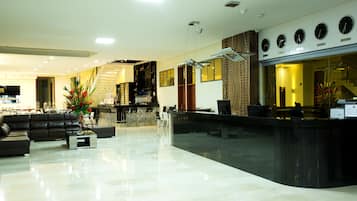 Un moderno vestíbulo de hotel con mostrador de recepción, zona de estar y una escalera.