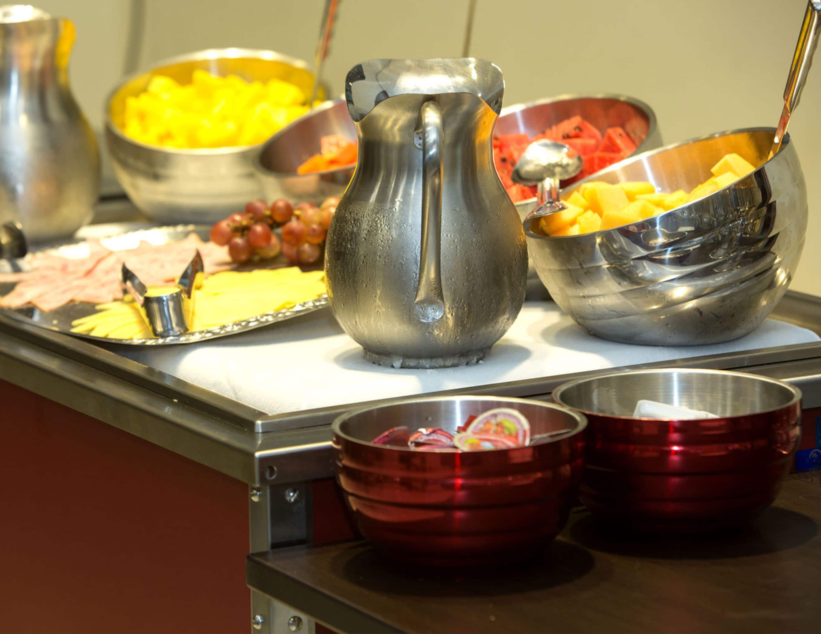 A buffet with various food items including fruits, cheeses, and meats.