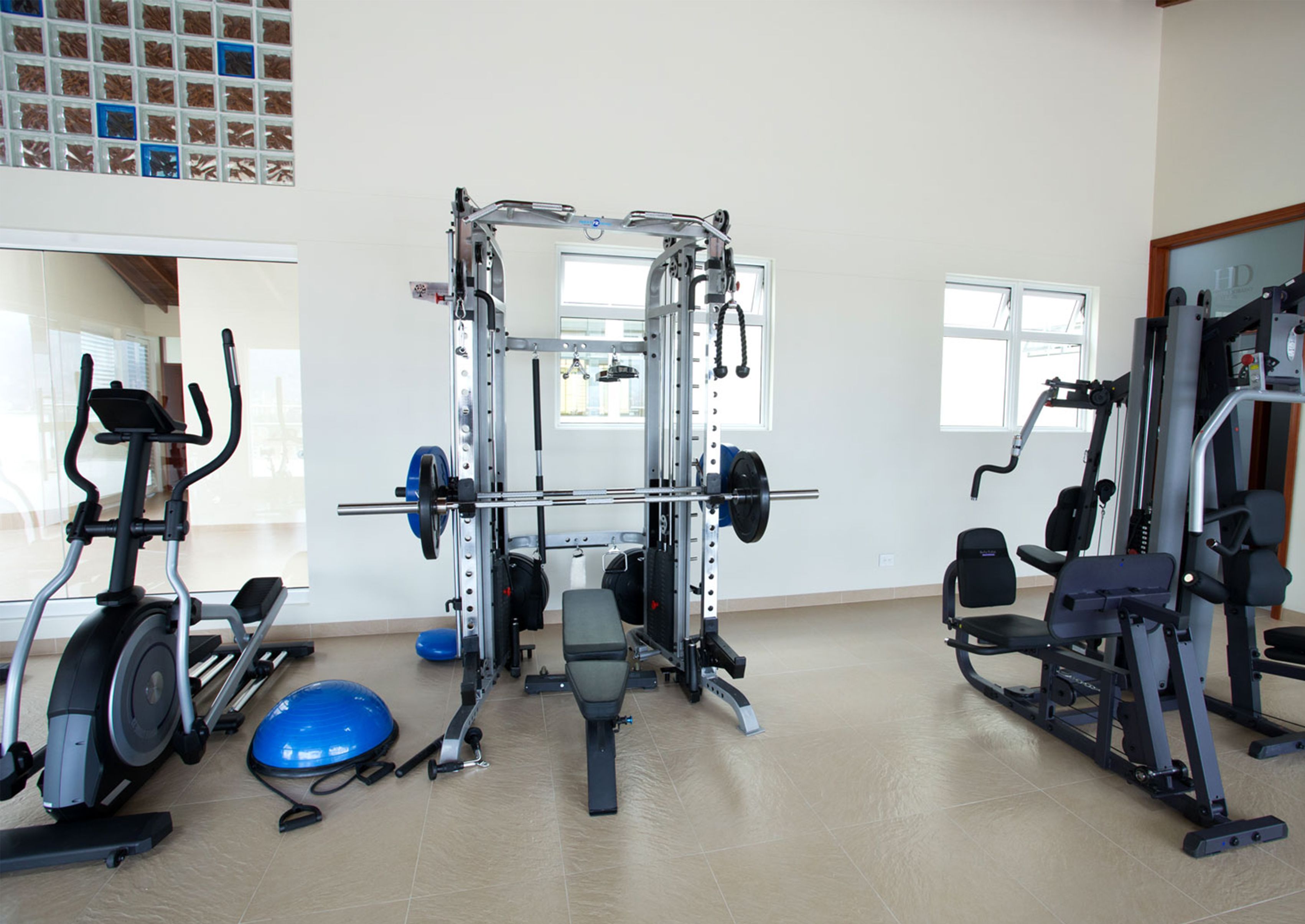 A gym with various exercise equipment including a weight bench, elliptical, and a squat rack.
