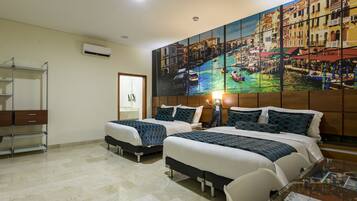 A hotel room with two beds, a wooden headboard, a glass table, and a cityscape painting on the wall.
