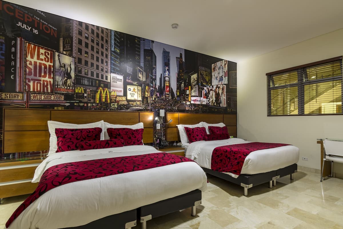 Een hotelkamer met twee bedden, een groot poster van Times Square en een bureau.