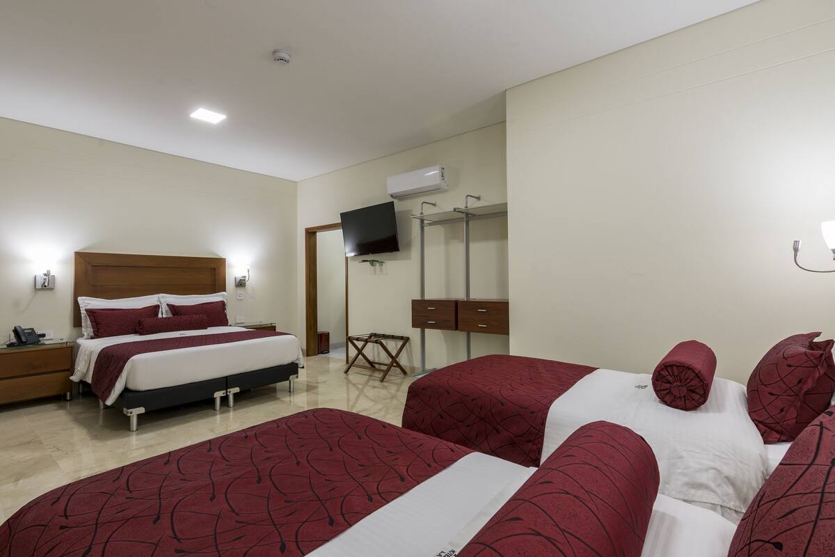 Een hotelkamer met een bed, nachtkastjes, een televisie, een kledingkast en een spiegel.