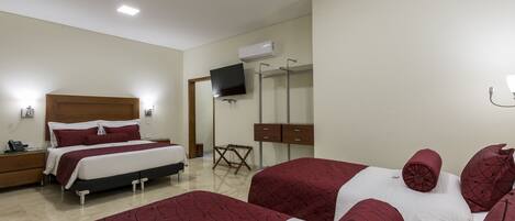Una habitación de hotel con cama, mesitas de noche, televisor, armario y espejo.