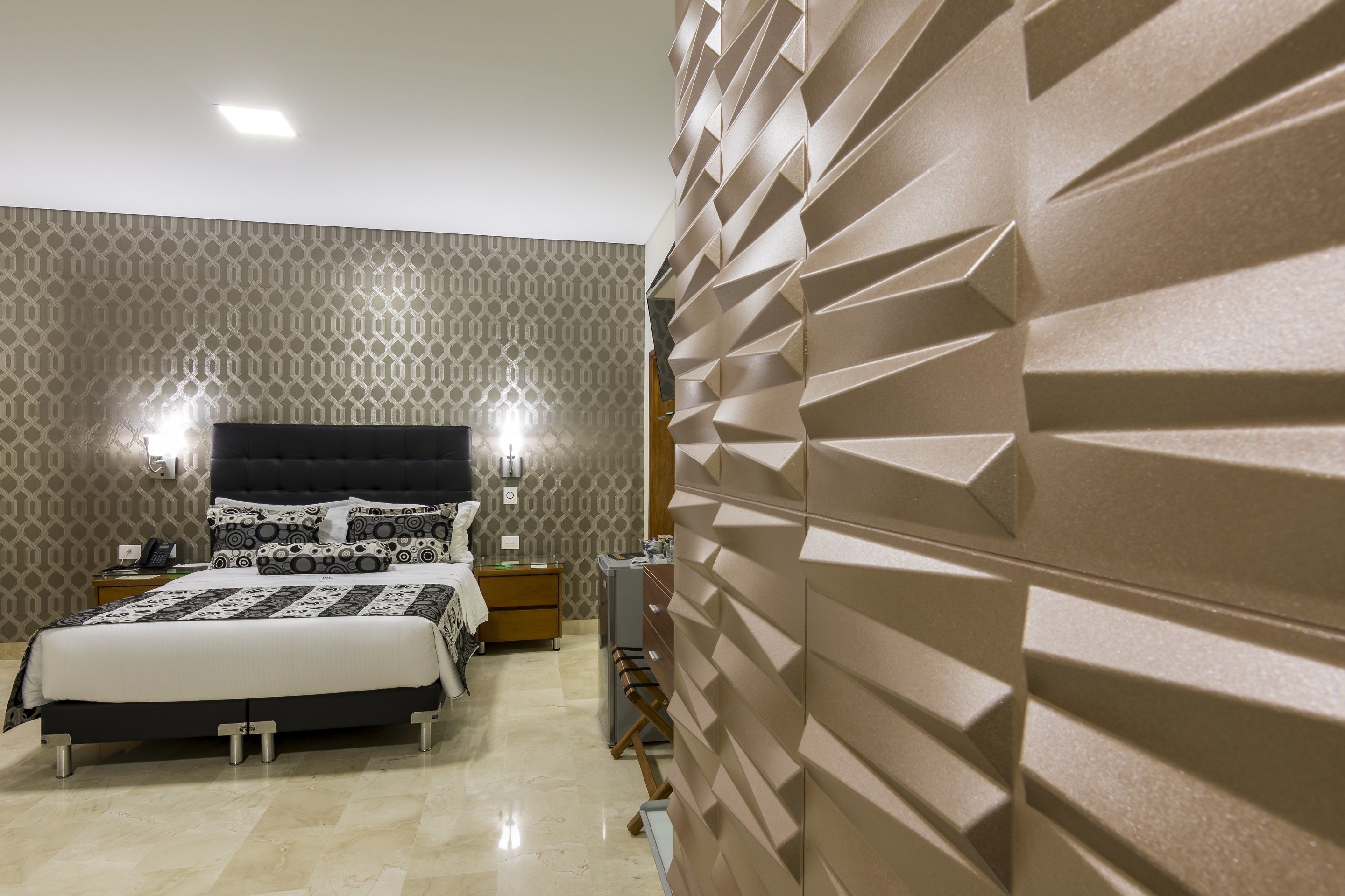 A modern bedroom with a large bed, patterned wallpaper, and a textured accent wall.
