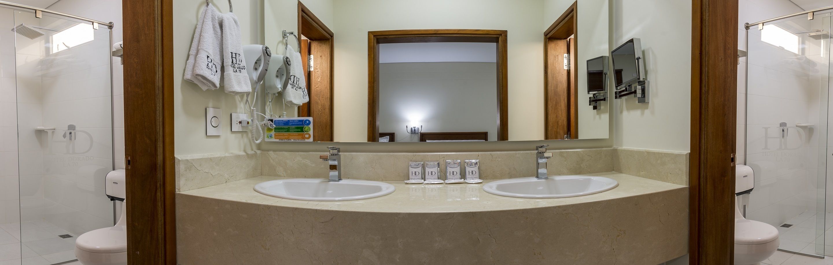 Un baño de hotel con dos lavamanos, un espejo grande y una zona de ducha.