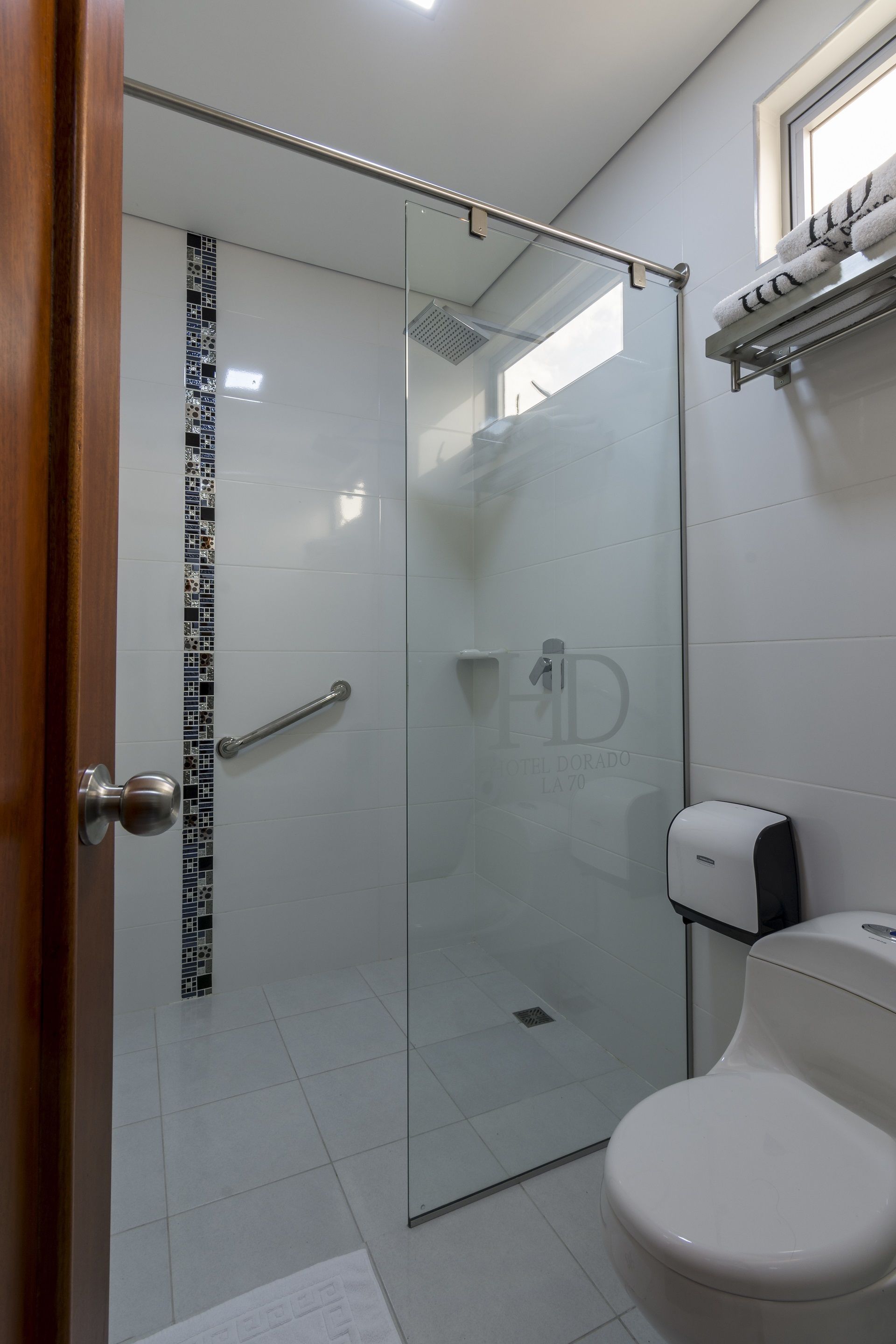 A bathroom with a glass shower enclosure, a toilet, and a hand dryer.