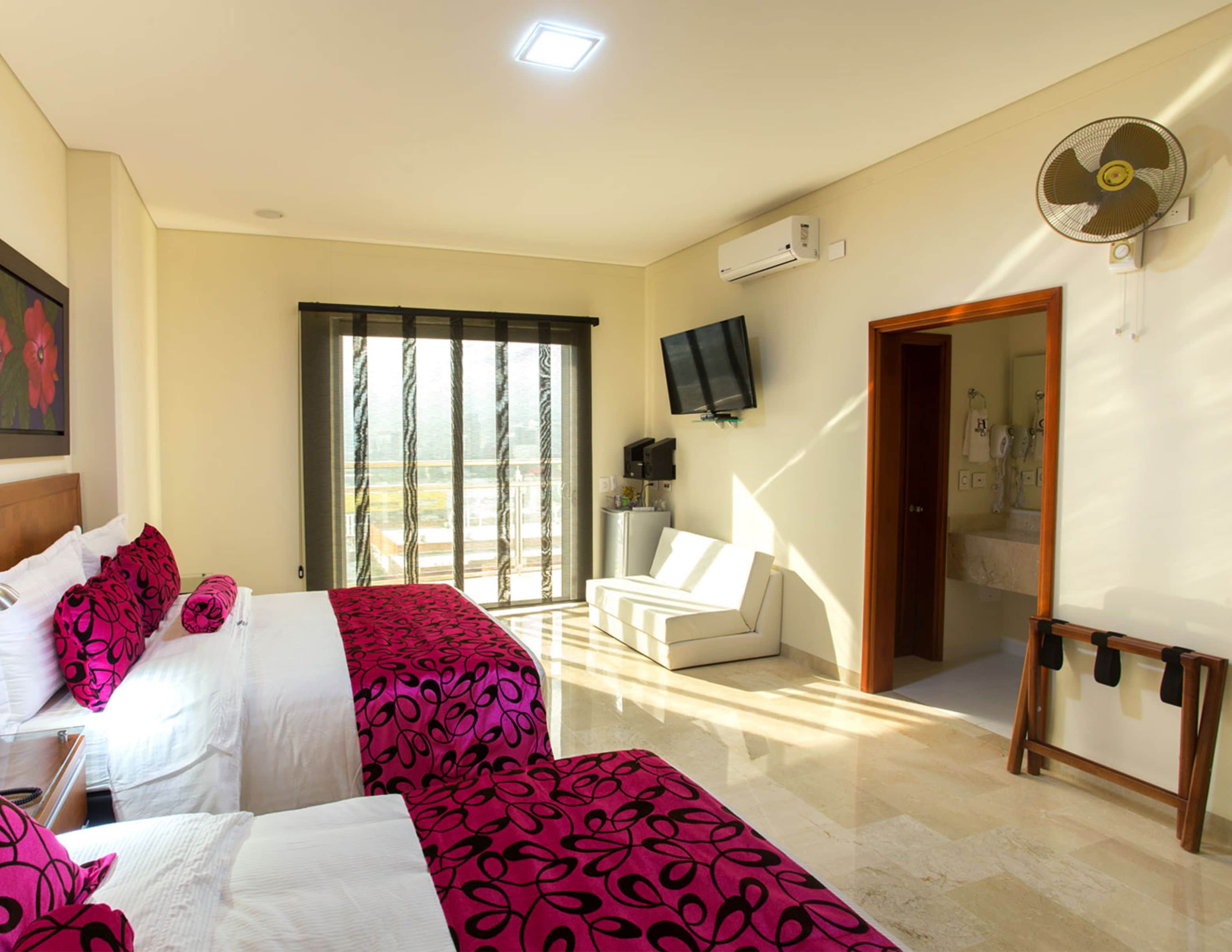 Una camera d'albergo con un letto, un divano, una TV e un bagno.