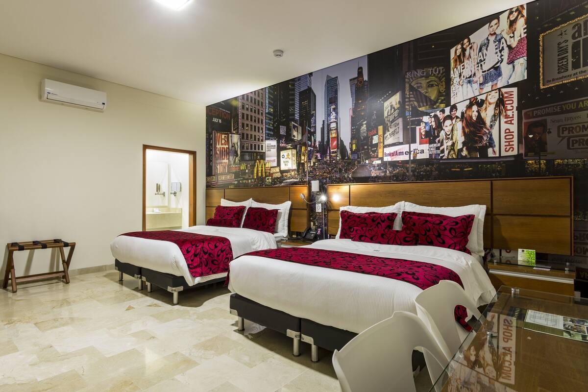 Een hotelkamer met twee bedden, een bureau, een stoel, een groot stadsgezicht-muurschildering en een houten hoofdeinde.