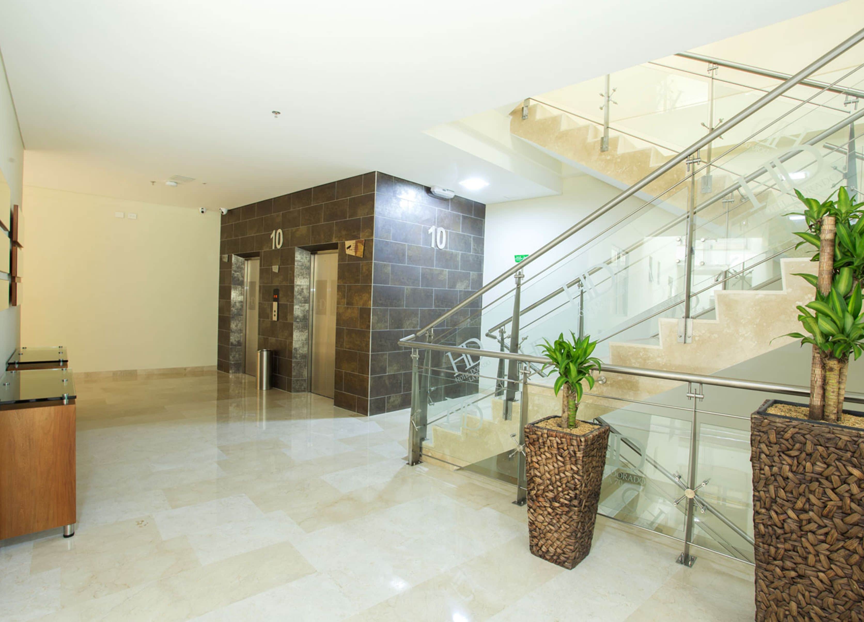 En moderne lobby med glastrappe, elevatorer og plantekasser.