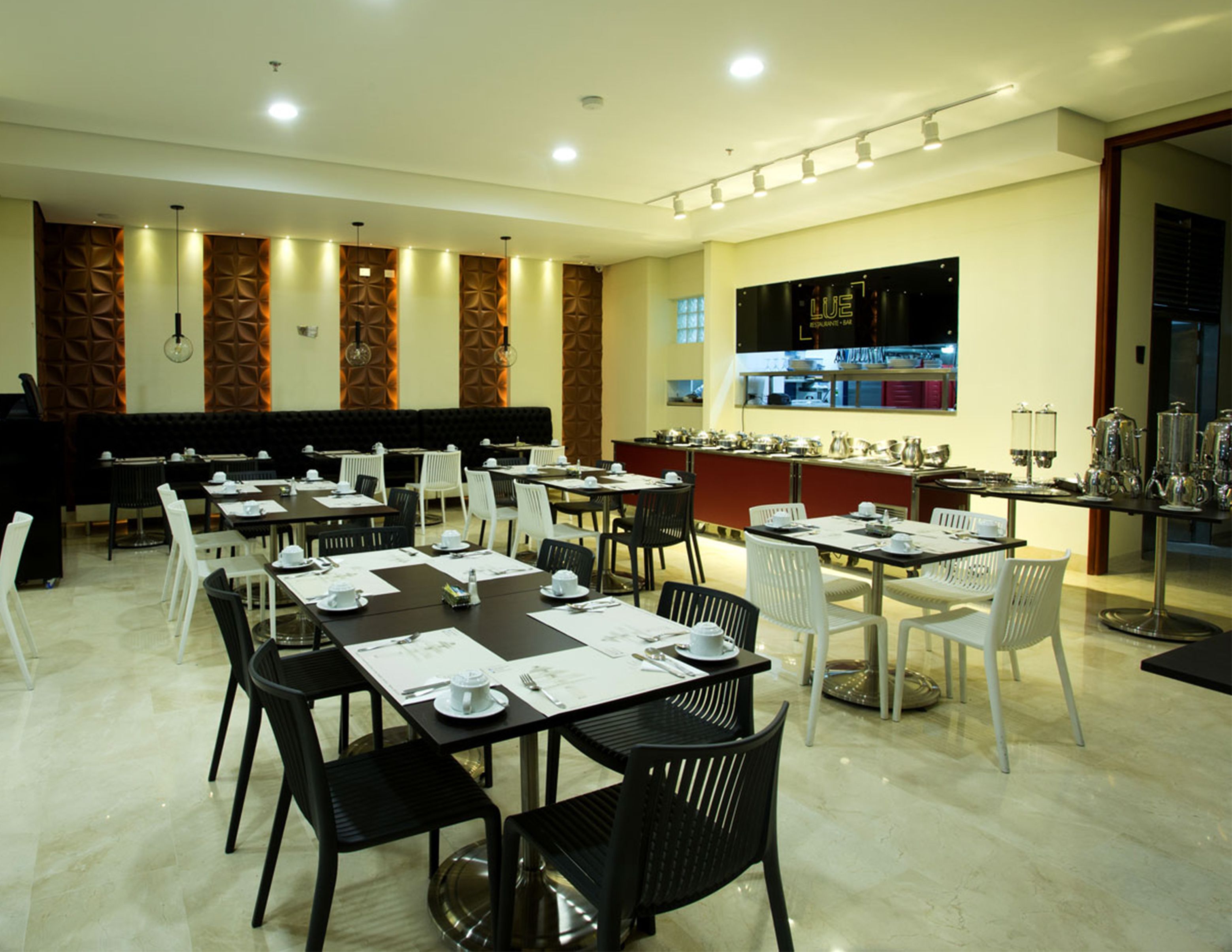 A spacious dining area with multiple tables and chairs, a counter with kitchen equipment, and a wall-mounted menu display.