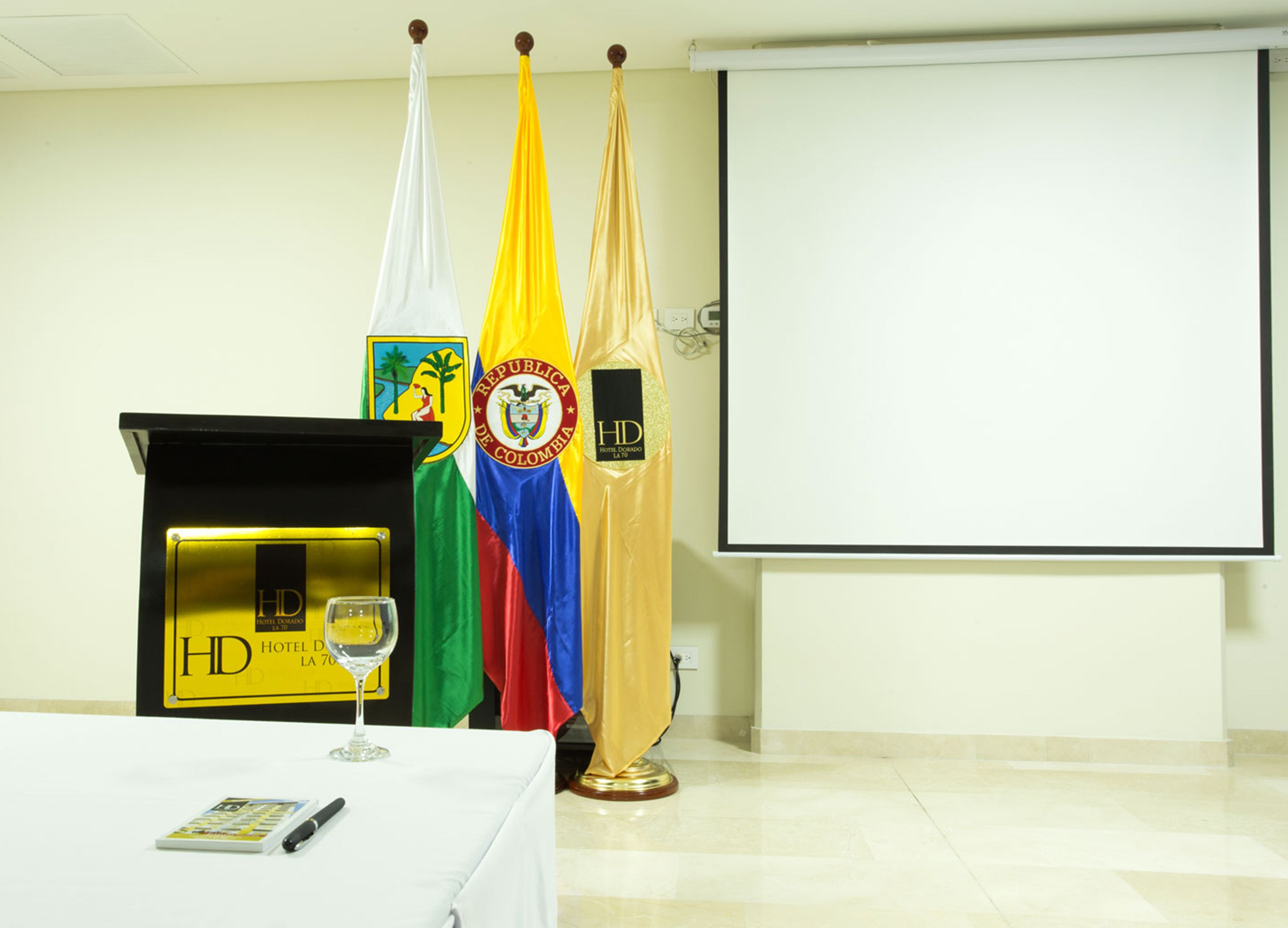 A conference room with a podium, HD Hotel La 70 logo, and three flags.