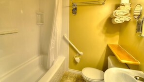 A bathroom with a bathtub, toilet, and a shower area. - Picket Fence Motel (St. Andrews)