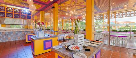 A vibrant buffet area with a colorful ceiling, a variety of food displays, and a view of the outdoor seating area.