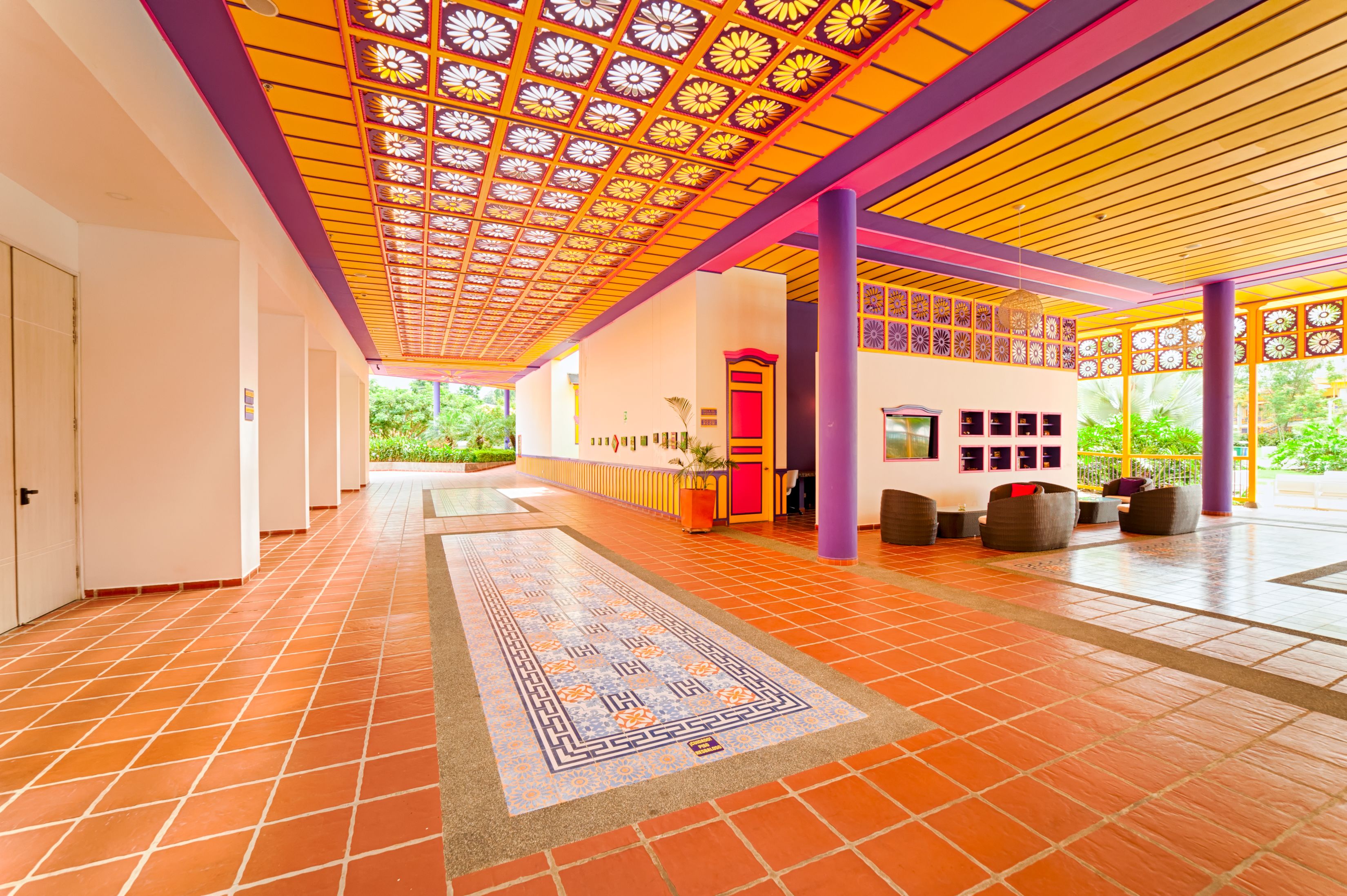 A corridor with patterned tiles, a decorative ceiling, and a seating area with cushions.