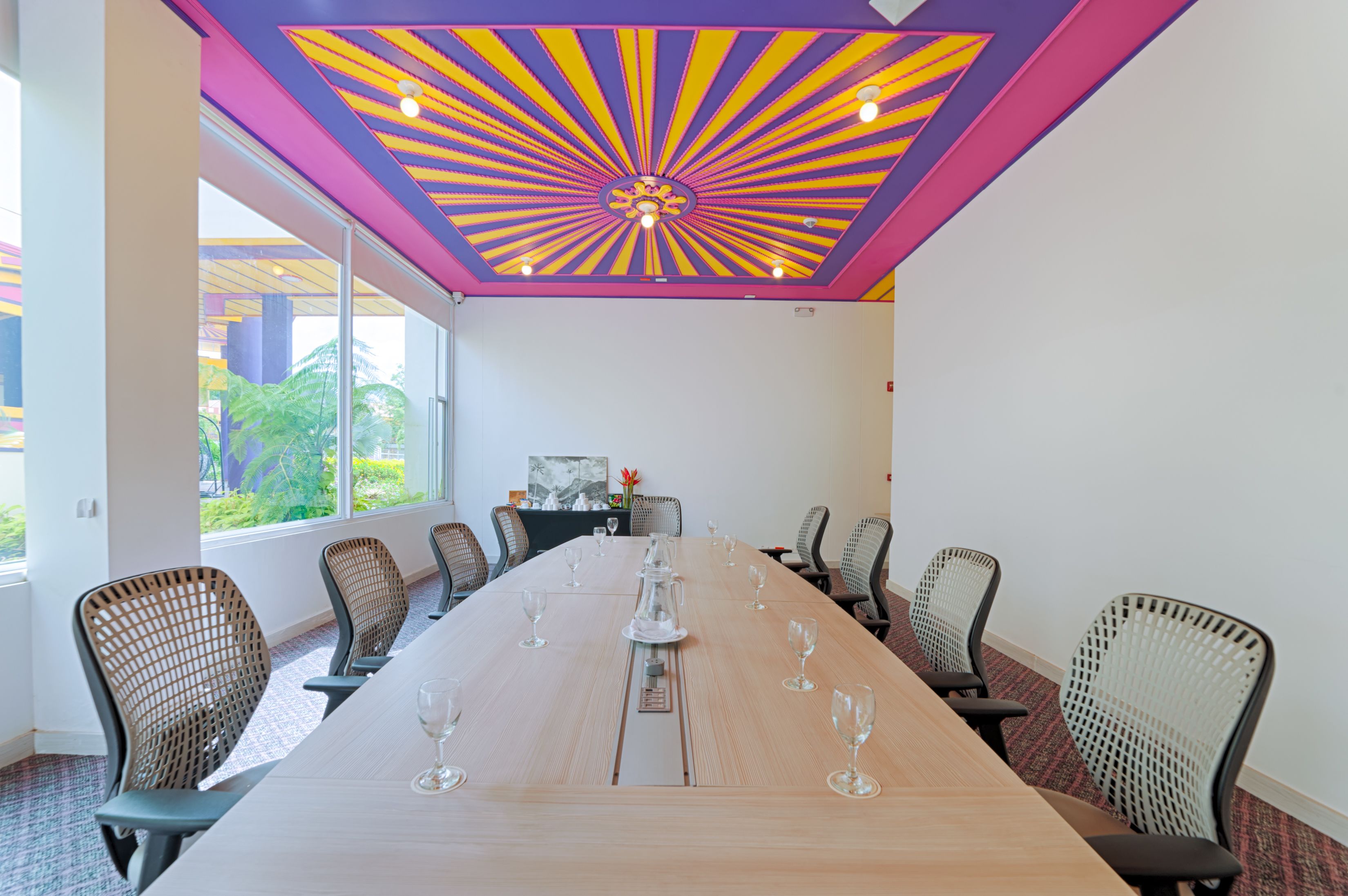 A conference room with a long table, chairs, and a colorful ceiling design.