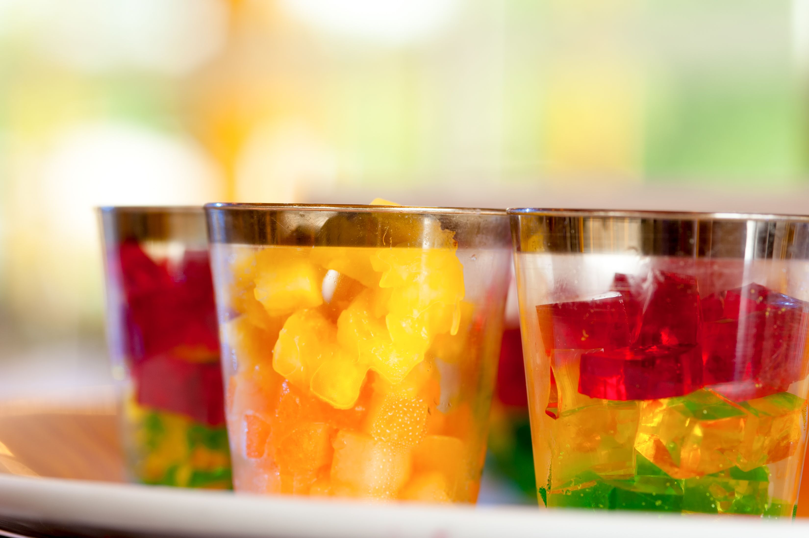 Three glasses of colorful fruit jelly with a blurred background.
