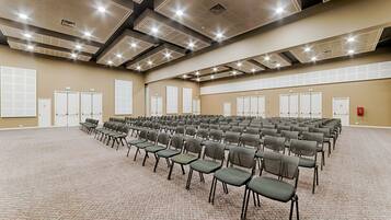 A large conference room with rows of chairs, carpeted floor, and a high ceiling with recessed lighting.
