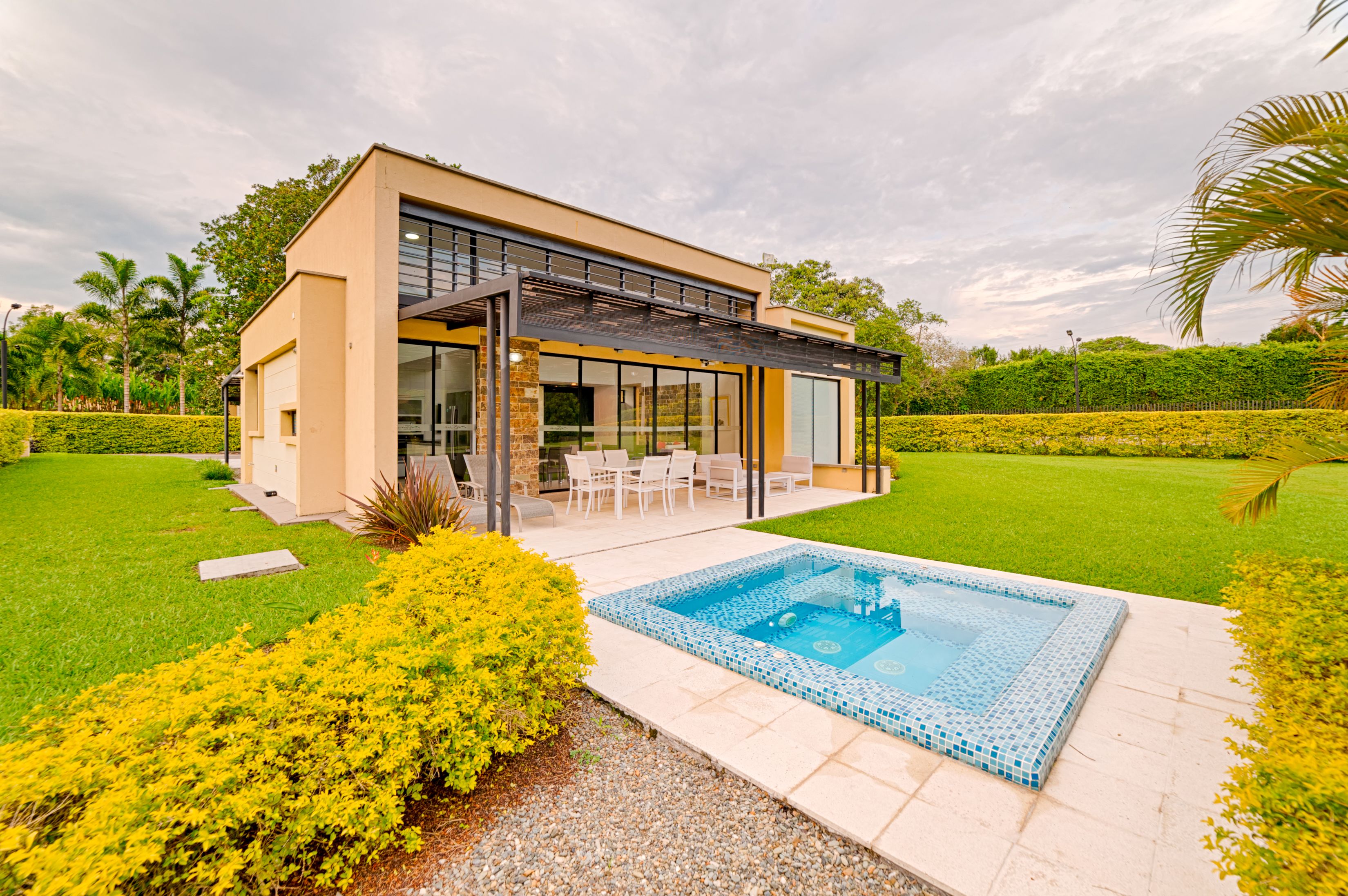 Una casa moderna con fachada de vidrio, piscina y césped cuidado.