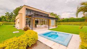 Una casa moderna con fachada de vidrio, piscina y césped cuidado.