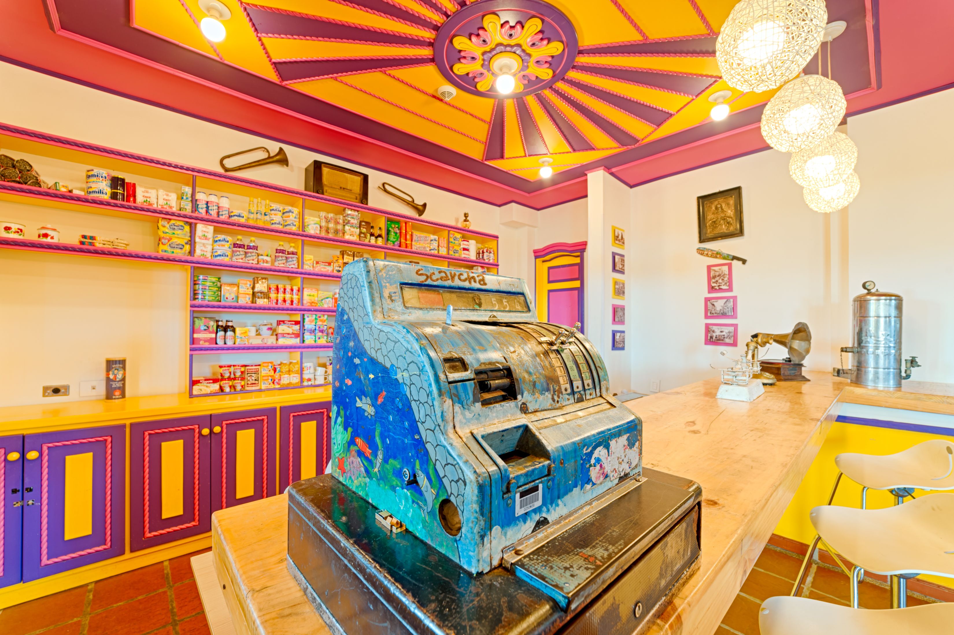 A brightly colored room with a vintage slot machine, shelves with various items, and a unique ceiling design.