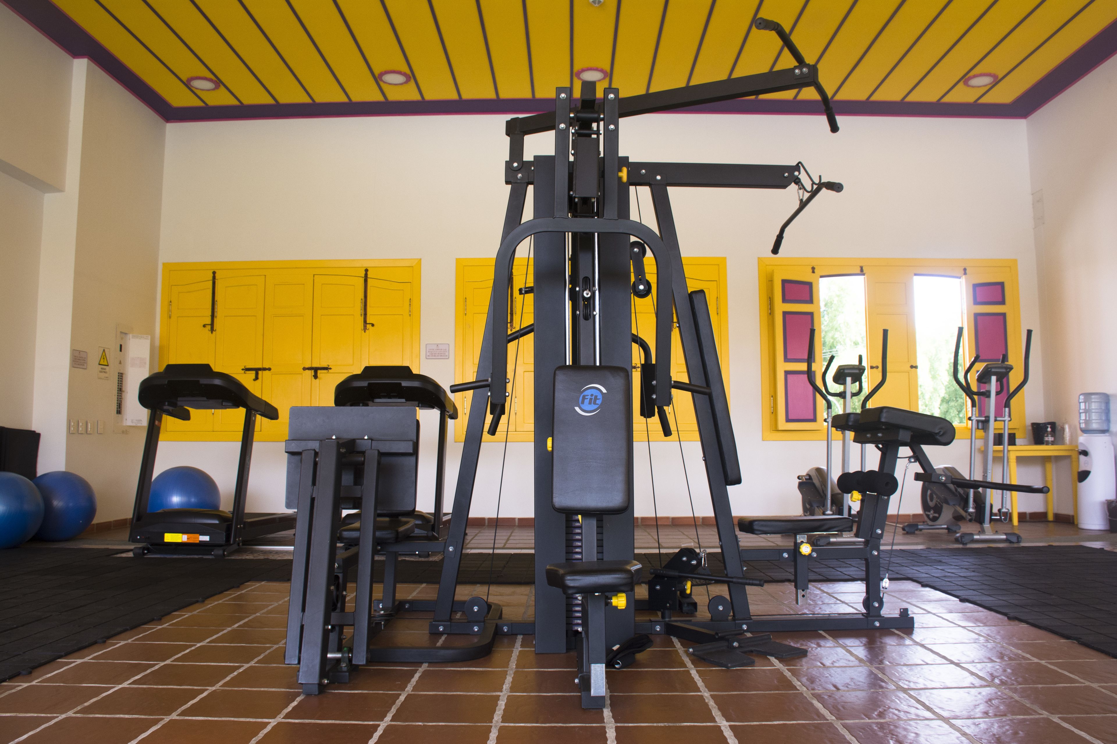 Un gimnasio con equipo de ejercicio, cintas de correr y pelotas de fitness.