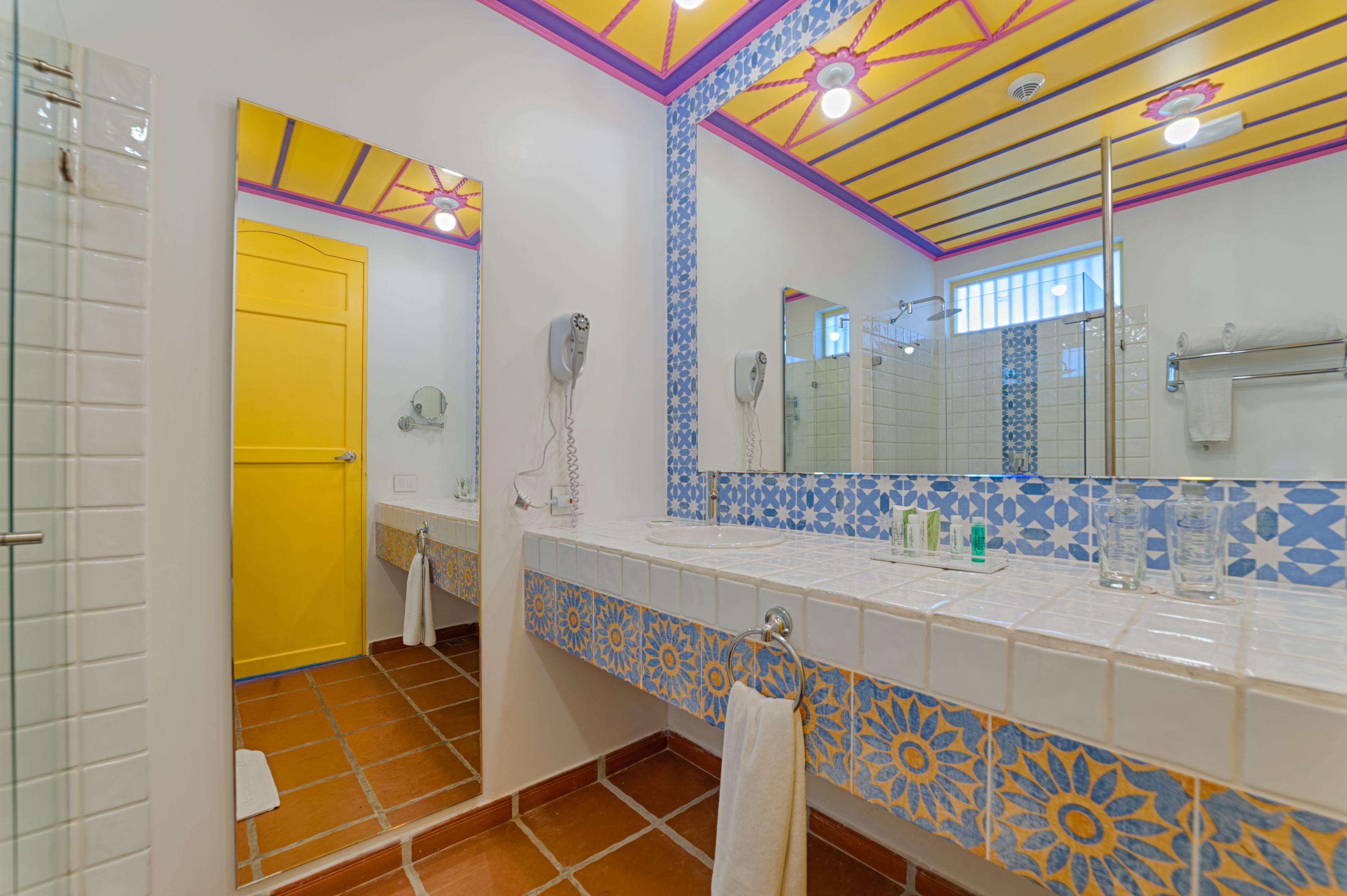 A bathroom with a yellow door, a large mirror, and a tiled backsplash.