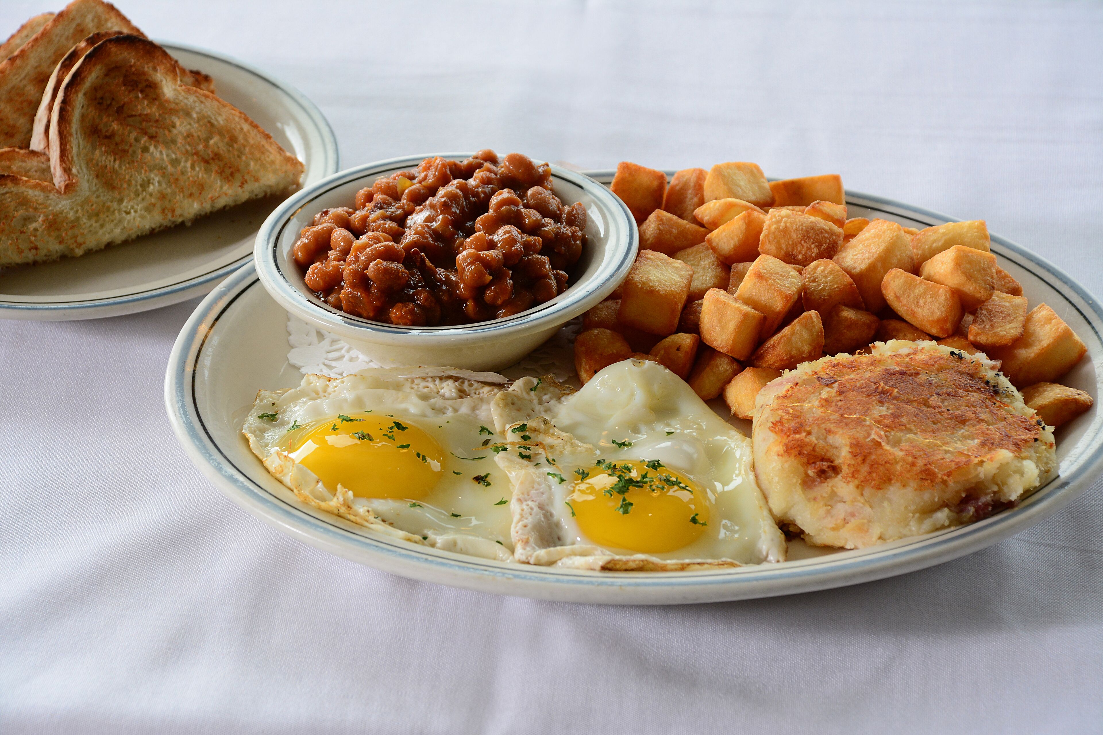 A plate with eggs, beans, hash browns, toast, and a patty.