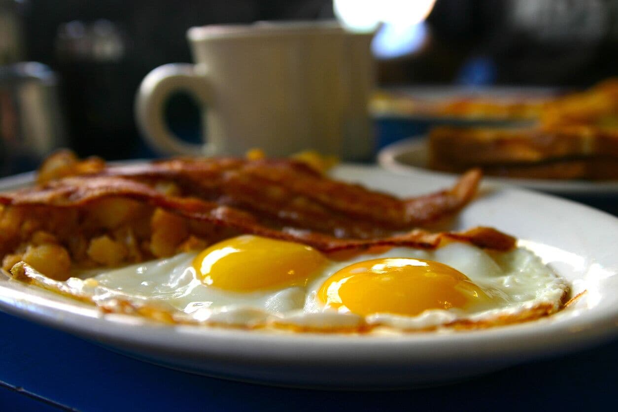 Une assiette de petit-déjeuner avec des œufs au plat et du bacon.