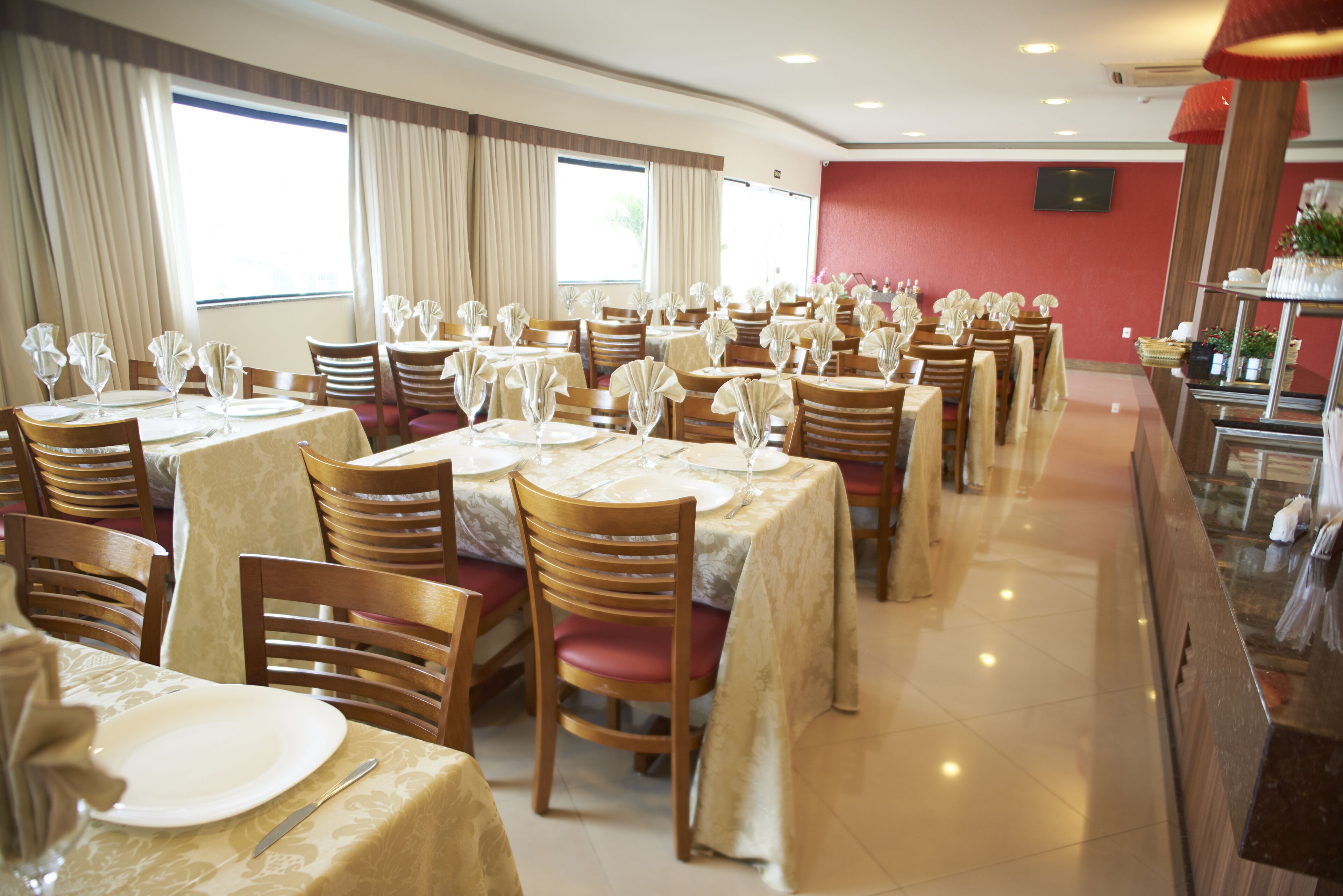 Un restaurante con varias mesas dispuestas, cubiertas con manteles blancos, sillas y cristalería.
