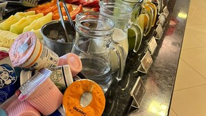 Ein Buffet mit verschiedenen Speisen und Getränken, darunter Obst, Joghurt und Saftspendern.