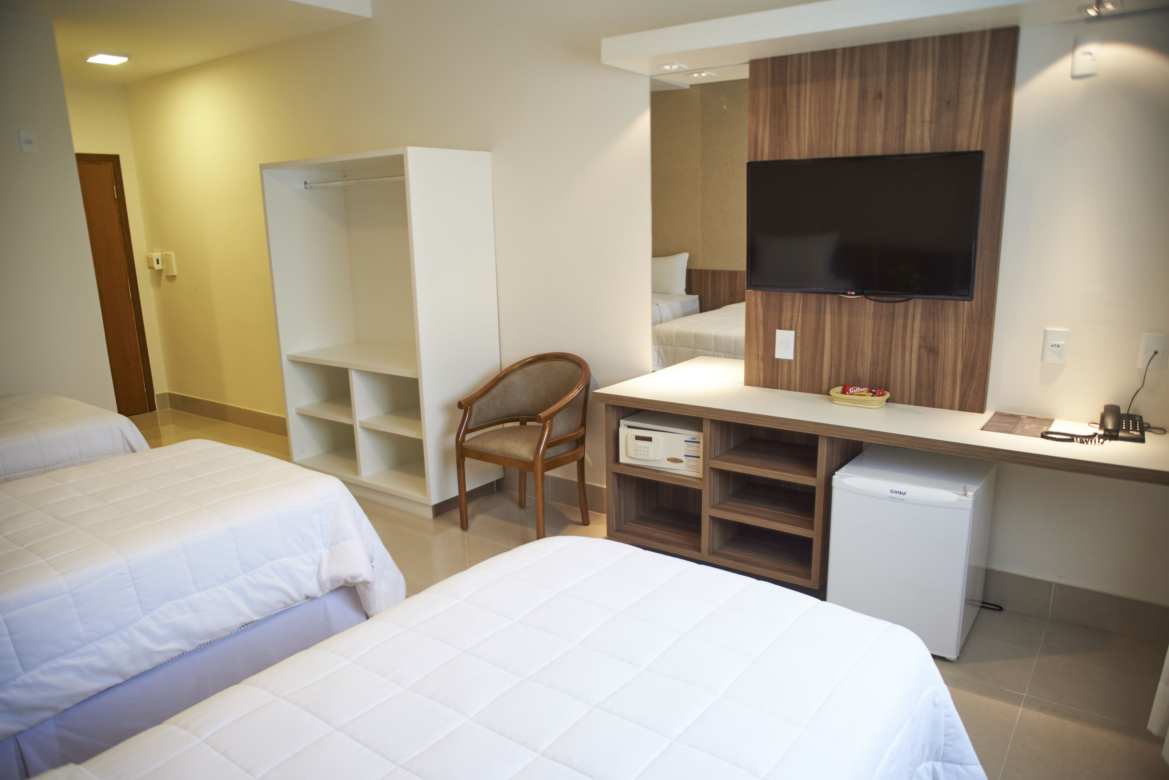 Habitación de hotel con dos camas, un escritorio, una silla, un televisor y un minibar.