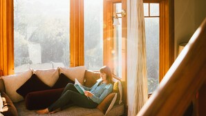 A cozy room with a large window, a wooden staircase, and a hanging light fixture. - Olema House at Point Reyes (Olema)